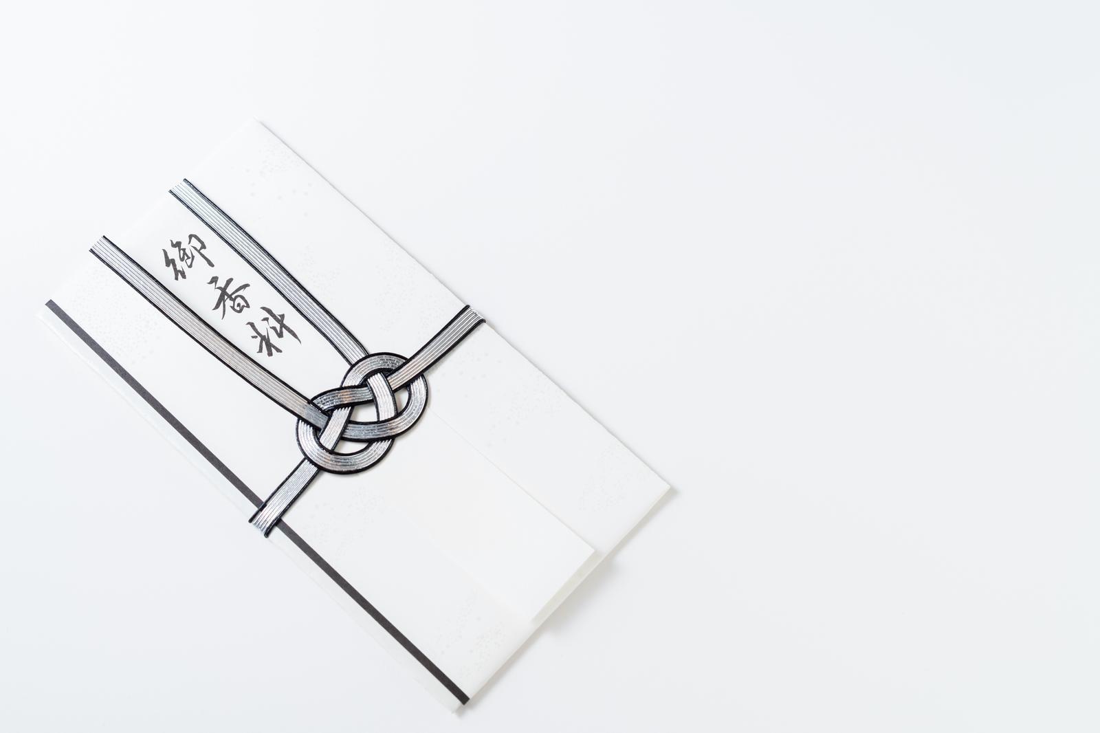 白い背景に置かれた御香典と書かれた不祝儀袋と黒白の水引