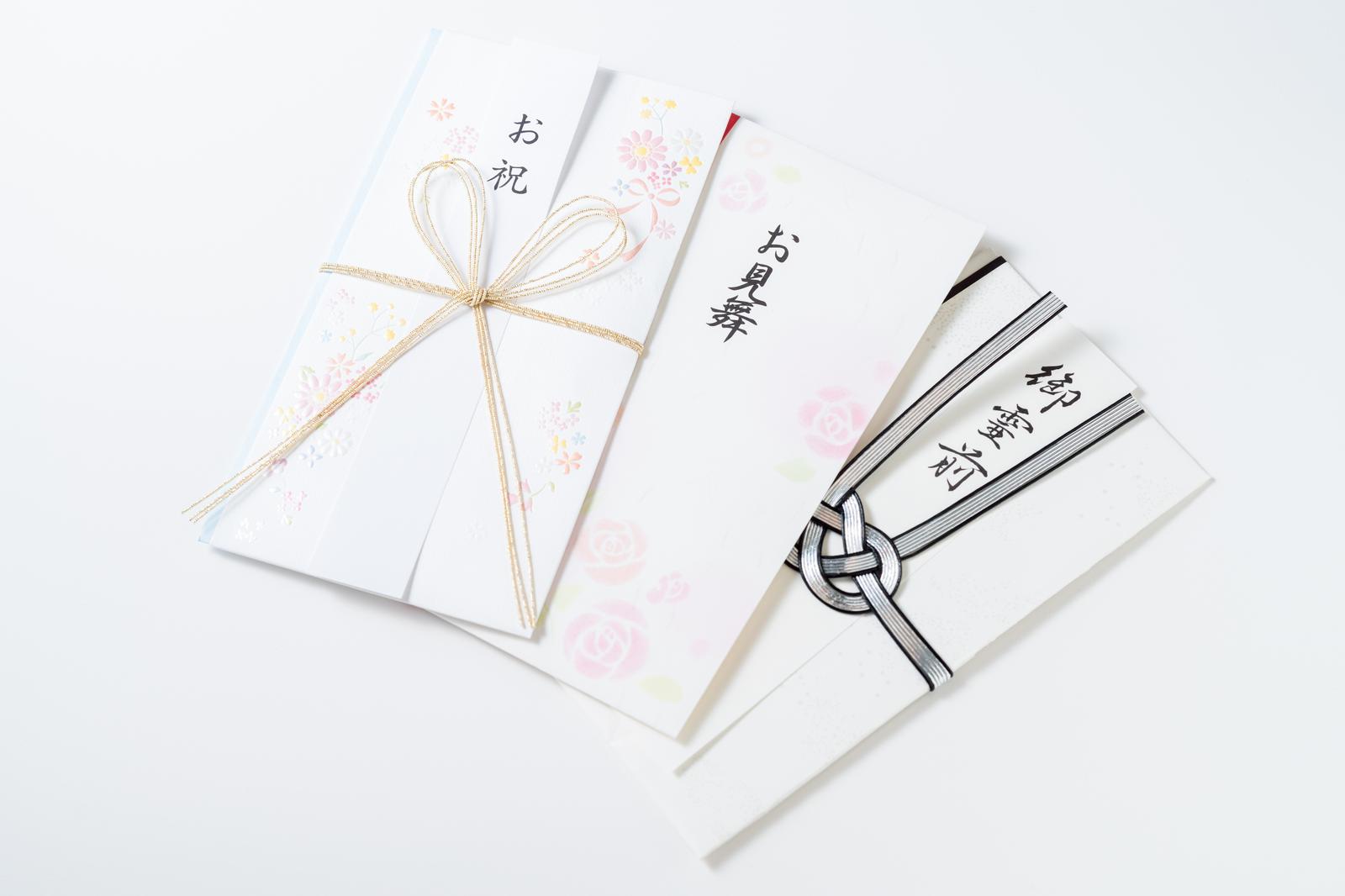 白背景に置かれた桜柄の祝儀袋と白無地の不祝儀袋