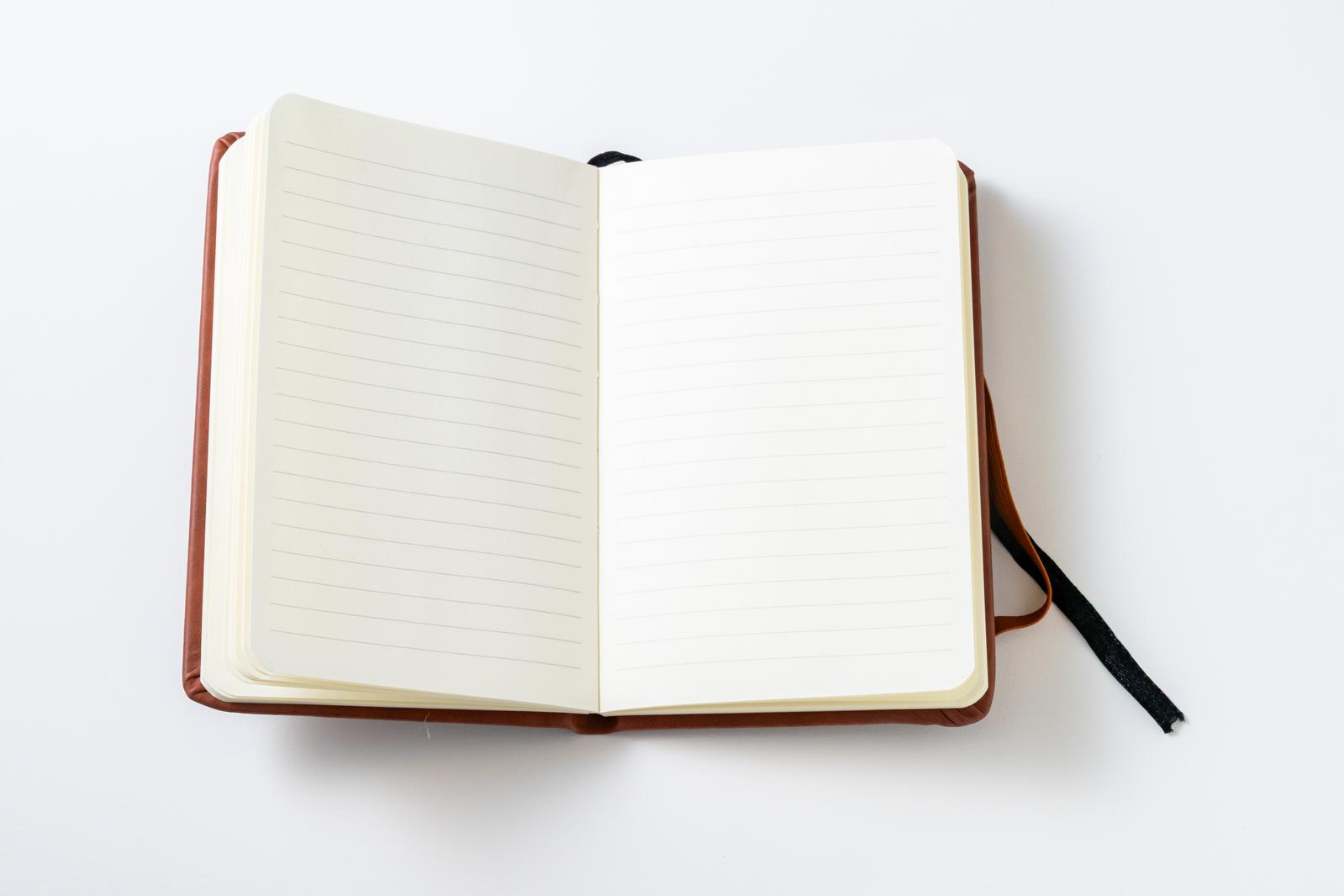 茶色の革表紙で見開きになった手帳、左に横罫線、右に白紙ページ