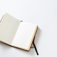 罫線入りの白いページが開かれた手帳とペンの写真