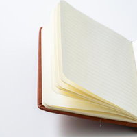 白背景に開かれた茶色の表紙のノートブックの写真