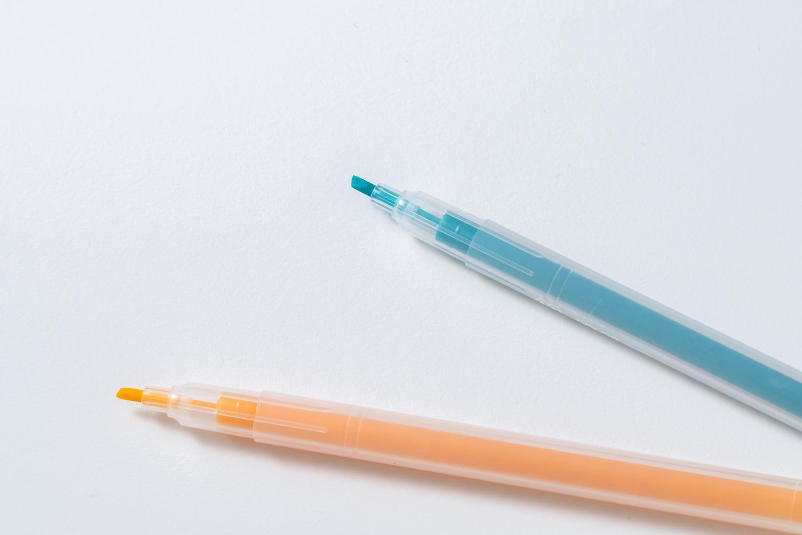 Two multicolor pens in orange and blue placed on a white background