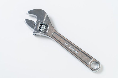 白背景に置かれたシルバーのモンキーレンチと作業工具