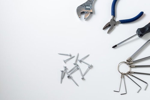 白い背景に配置された作業工具とネジ、六角レンチ