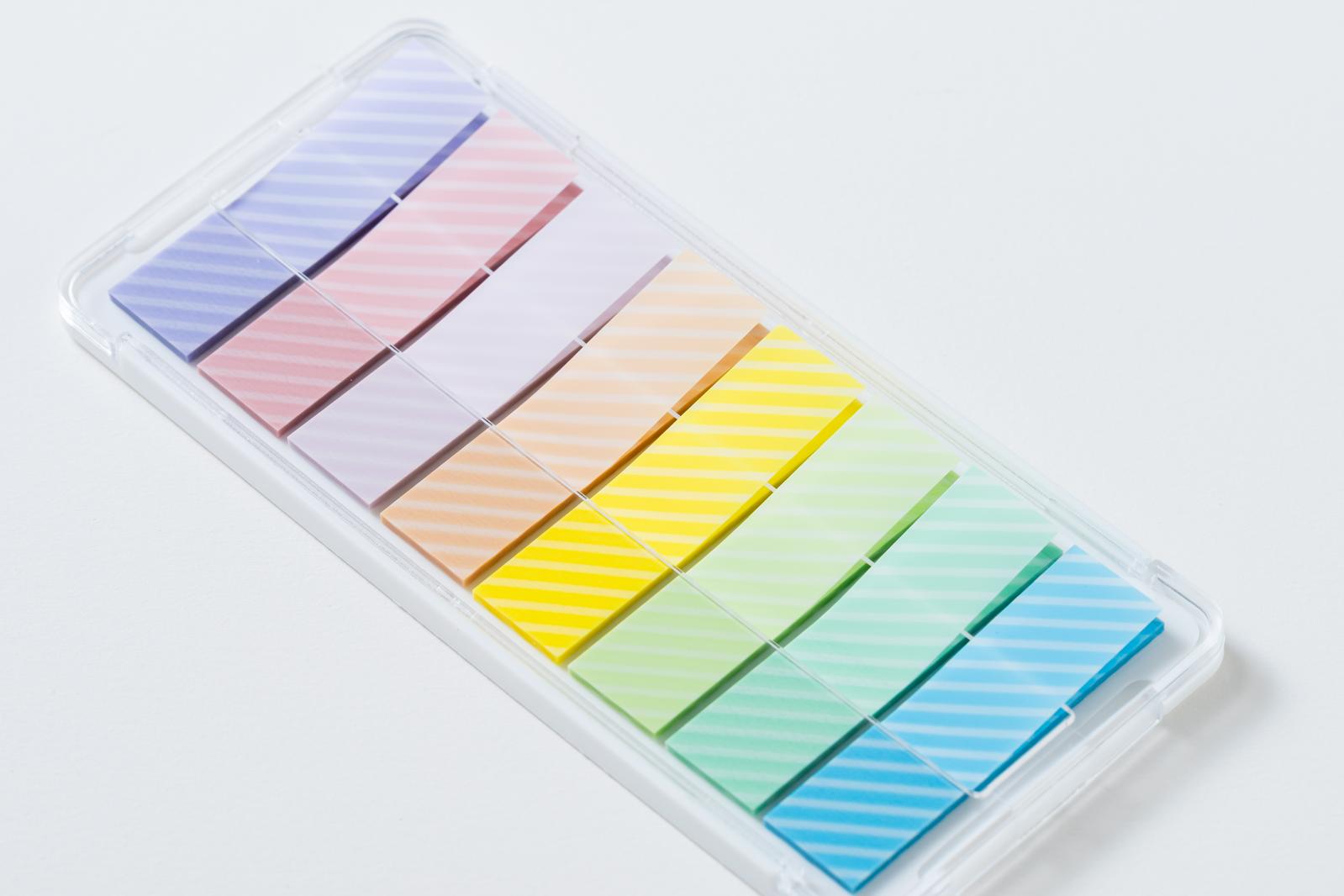 Rainbow-colored sticky notes (purple, pink, yellow, green, blue) organized in a transparent plastic case