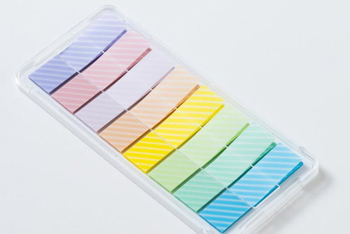 レインボーカラーの付箋が透明プラスチックケースに整理された状態
