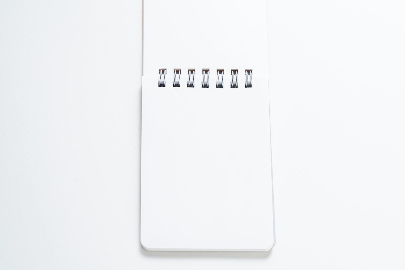 A white ring-bound notebook placed on a white background