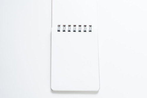 白背景に置かれたリング式メモ帳と文具ステーショナリー