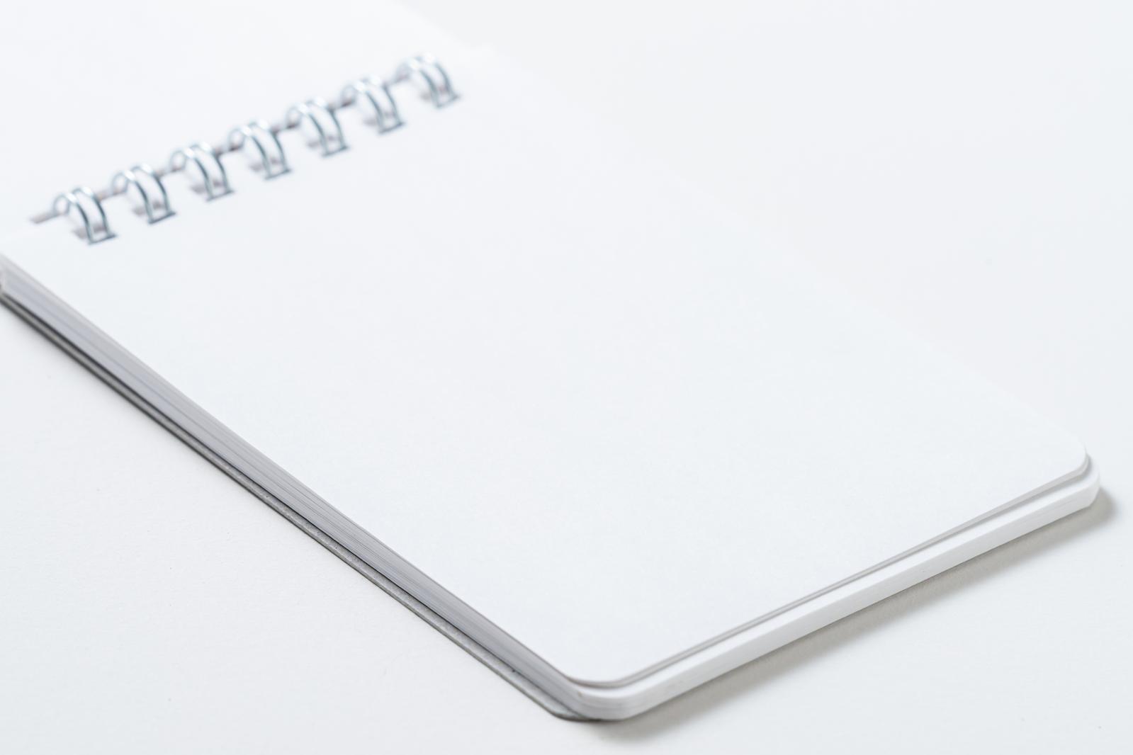 白い表紙のリングノートが斜めに配置された文具の写真