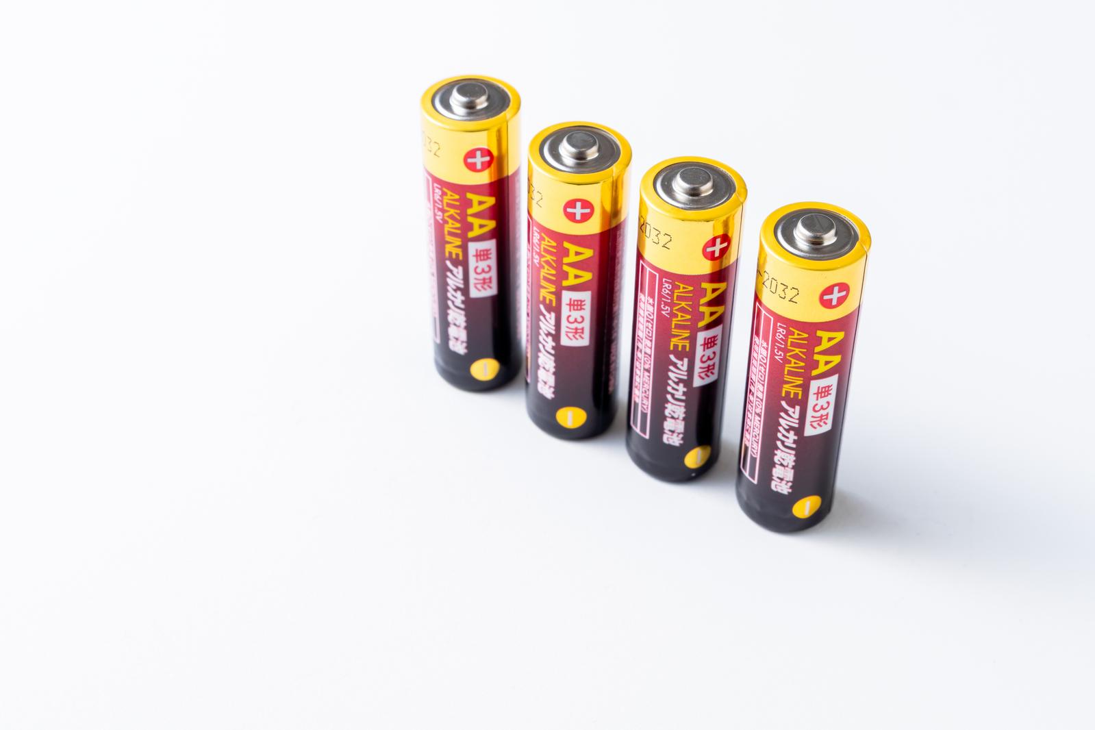 Four alkaline batteries arranged diagonally on a white background
