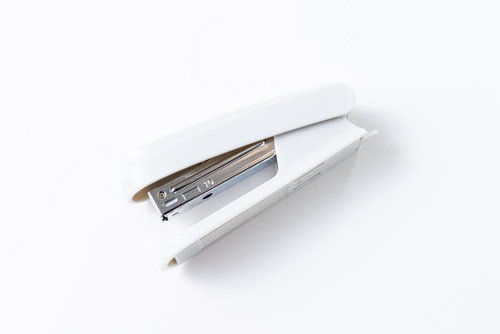 白いホチキスとペン、開いた状態で置かれた事務用品