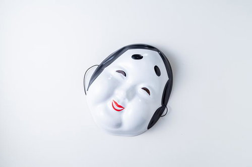 黒い髪紐をつけた白塗り面と赤い唇の伝統芸能用お面