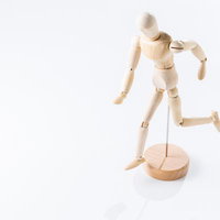 走るポーズを取る木製デッサン人形と木製台座の写真