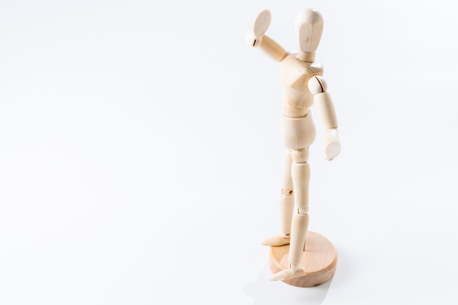 円形台座に立ち右腕を高く上げるポーズの木製デッサン人形