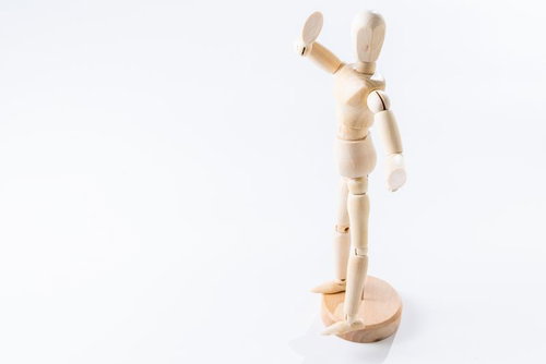 右腕を高く掲げる木製デッサン人形のポーズ