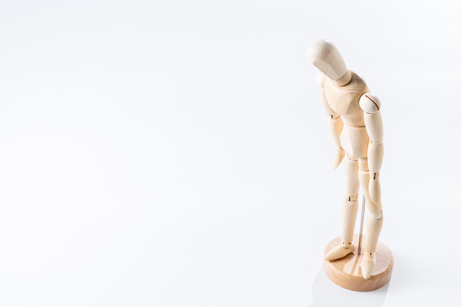 Wooden drawing mannequin in a pose with the right hand raised against a white background
