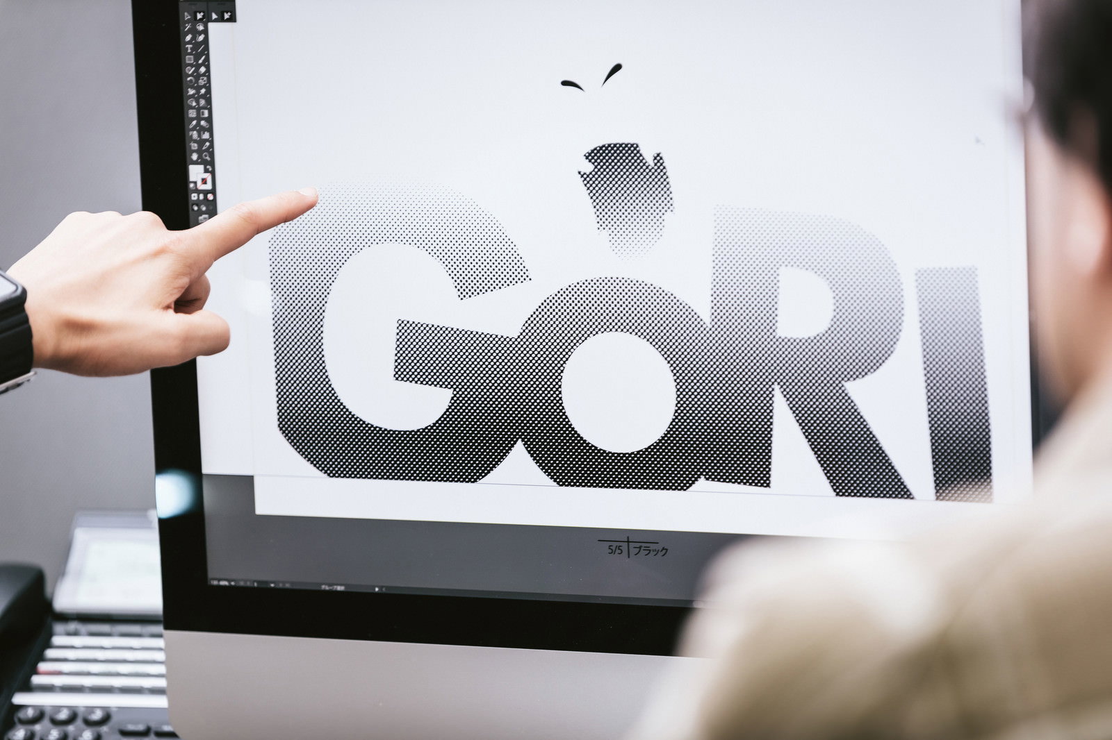 IllustratorでGORIロゴの網点グラデーションデザインを確認する男性