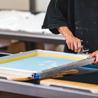 シルクスクリーン印刷でシルク版の位置を調整する職人の写真