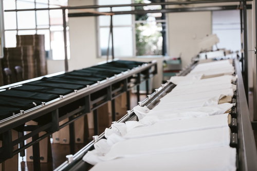 シルク印刷工場の長台に並ぶ白と黒のTシャツ