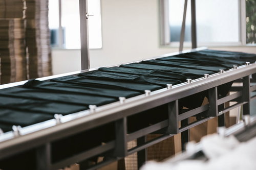 シルクスクリーン印刷工場の長台に置かれた黒Tシャツ