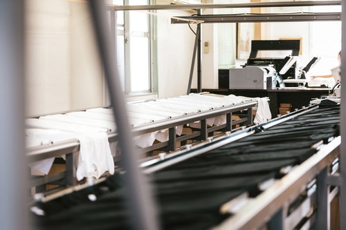 シルク印刷の長台に並べたTシャツのプリント準備