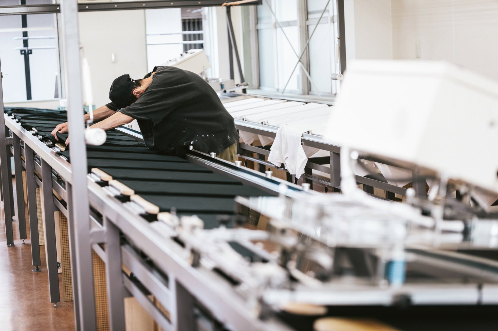 シルク印刷台で黒いTシャツの位置合わせを行う職人の手元