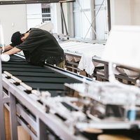 シルク印刷台に並べたTシャツの位置合わせを行う職人の写真