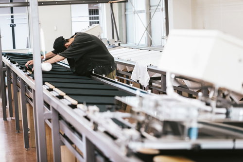 シルク印刷台に並べたTシャツの位置合わせを行う職人