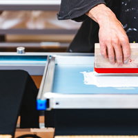 シルクスクリーン印刷でスキージを使う職人の手元の写真