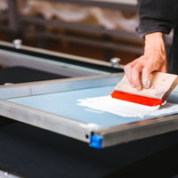 シルク版のインキを手刷りする様子の写真