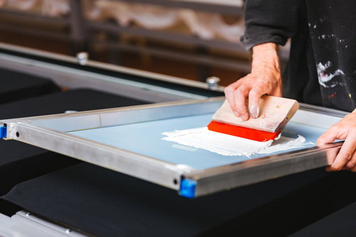 シルク版のインキを手刷りする様子