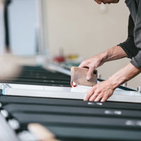 塗っては乾燥させる作業を繰り返すシルク印刷の職人の写真