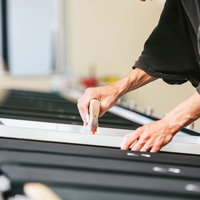 スキージを繰り返し使って着色するシルクスクリーン印刷の職人の写真