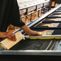 ズラリと並んだTシャツに手刷りで着色していく職人の写真