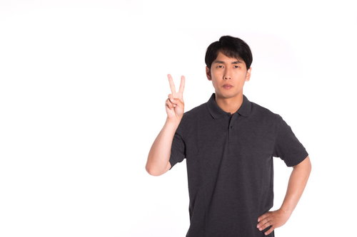 険しい顔でピースサインをする観光客