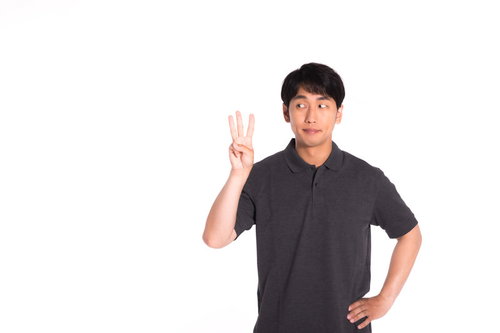 ランキング3位を示す3本指を立てるグレーポロシャツの男性