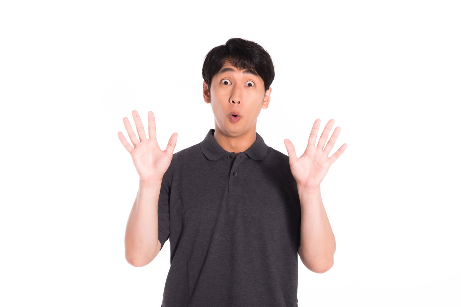 両手を上げて大きく口を開けて驚いている黒いTシャツの男性［モデル：大川竜弥］