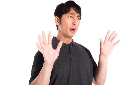 エアもみもみで驚く男性が両手で拒否する困惑した表情