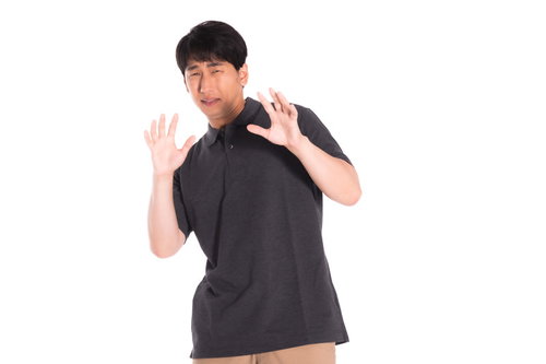 黒いシャツを着て両手を前に出す怖がる男性