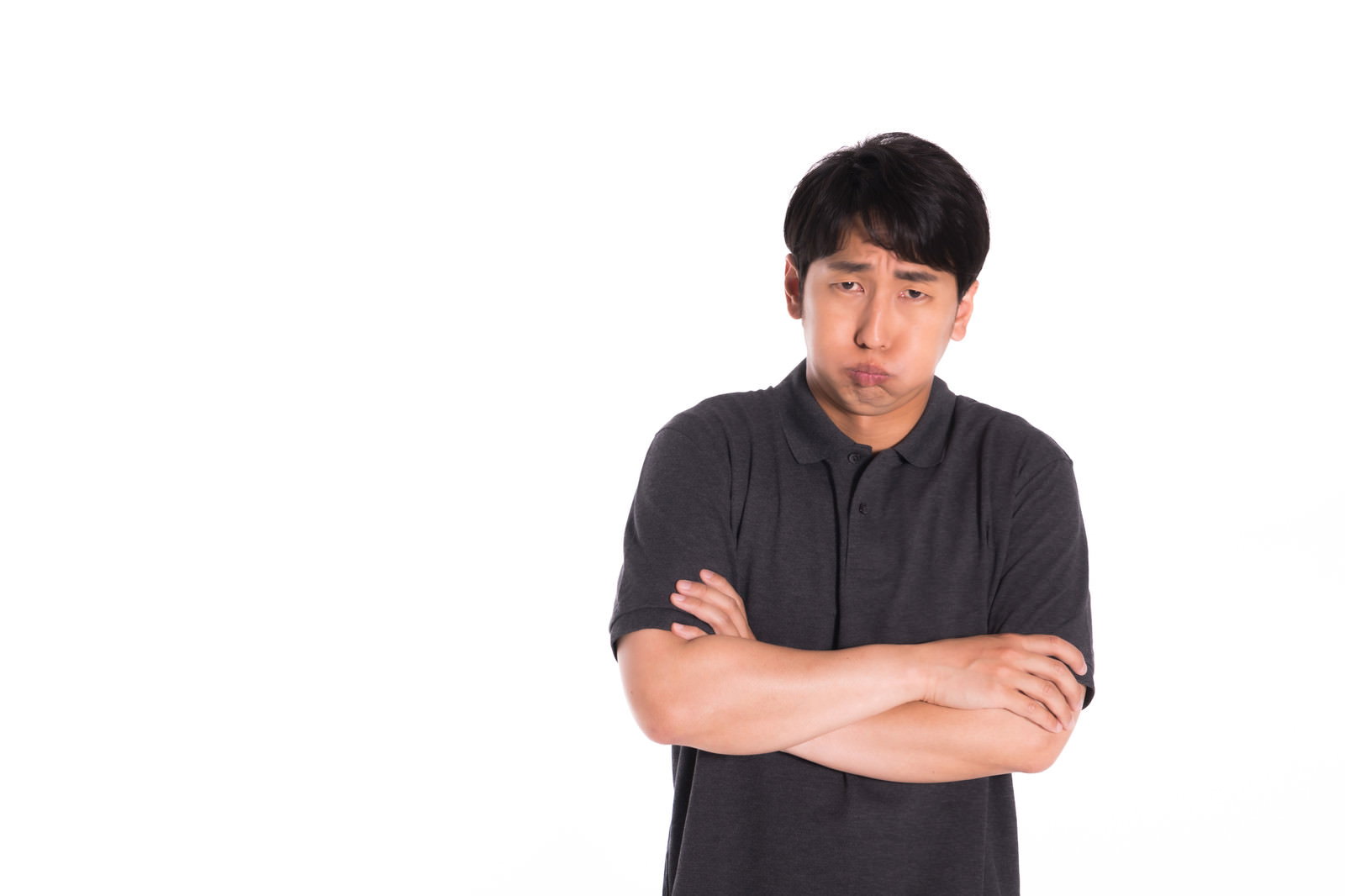頬を膨らませて腕組みをする怒った表情の男性［モデル：大川竜弥］