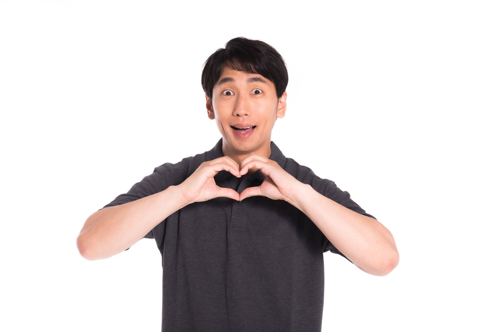 両手でハートポーズを作って笑顔を見せる黒いTシャツの男性［モデル：大川竜弥］