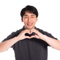 両手でハートのポーズを作る幸せそうな笑みの写真