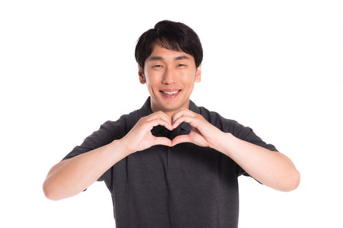 両手でハートのポーズを作る幸せそうな笑み