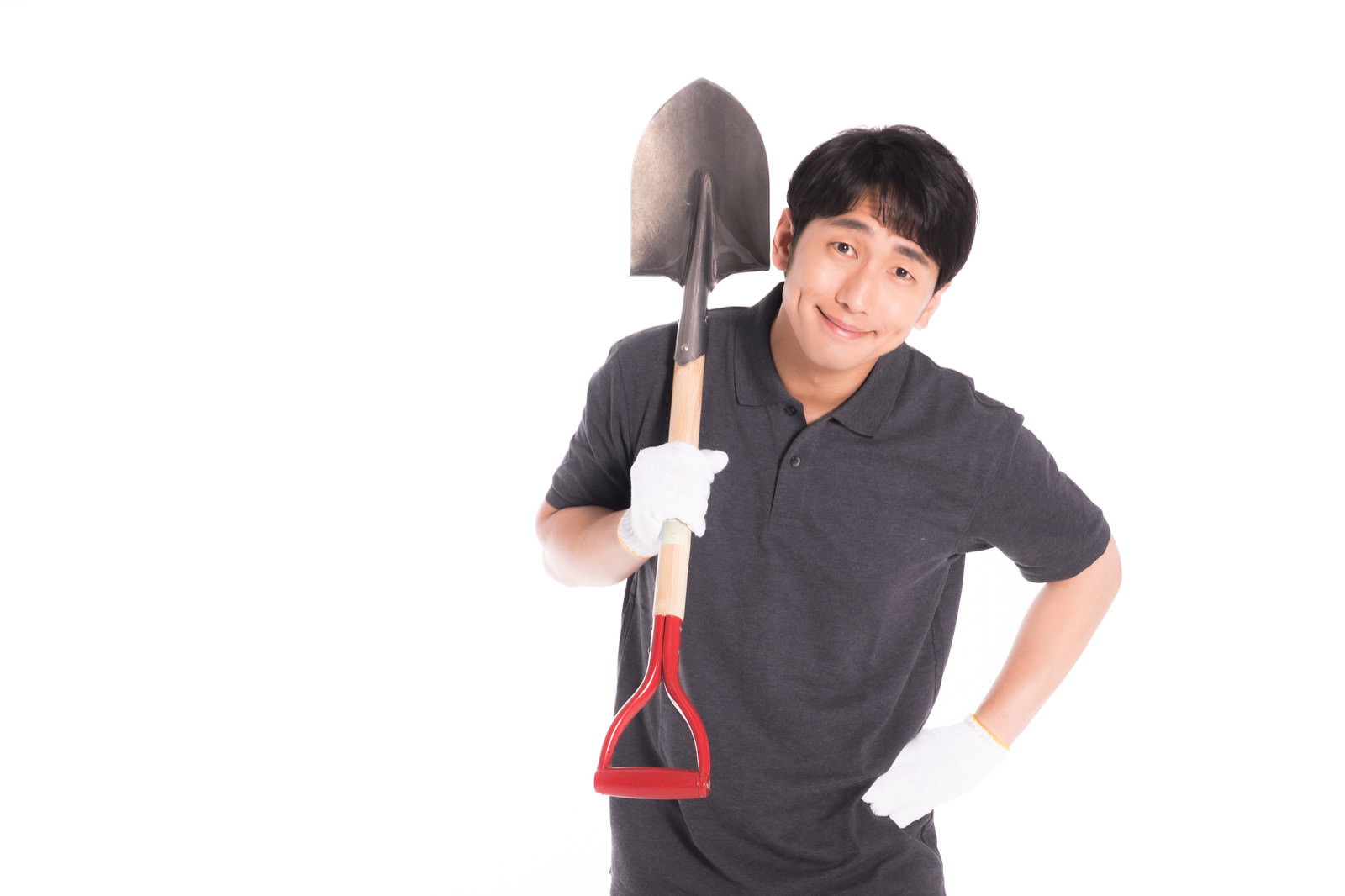 A man in a black polo shirt wearing white gloves, smiling while holding a shovel