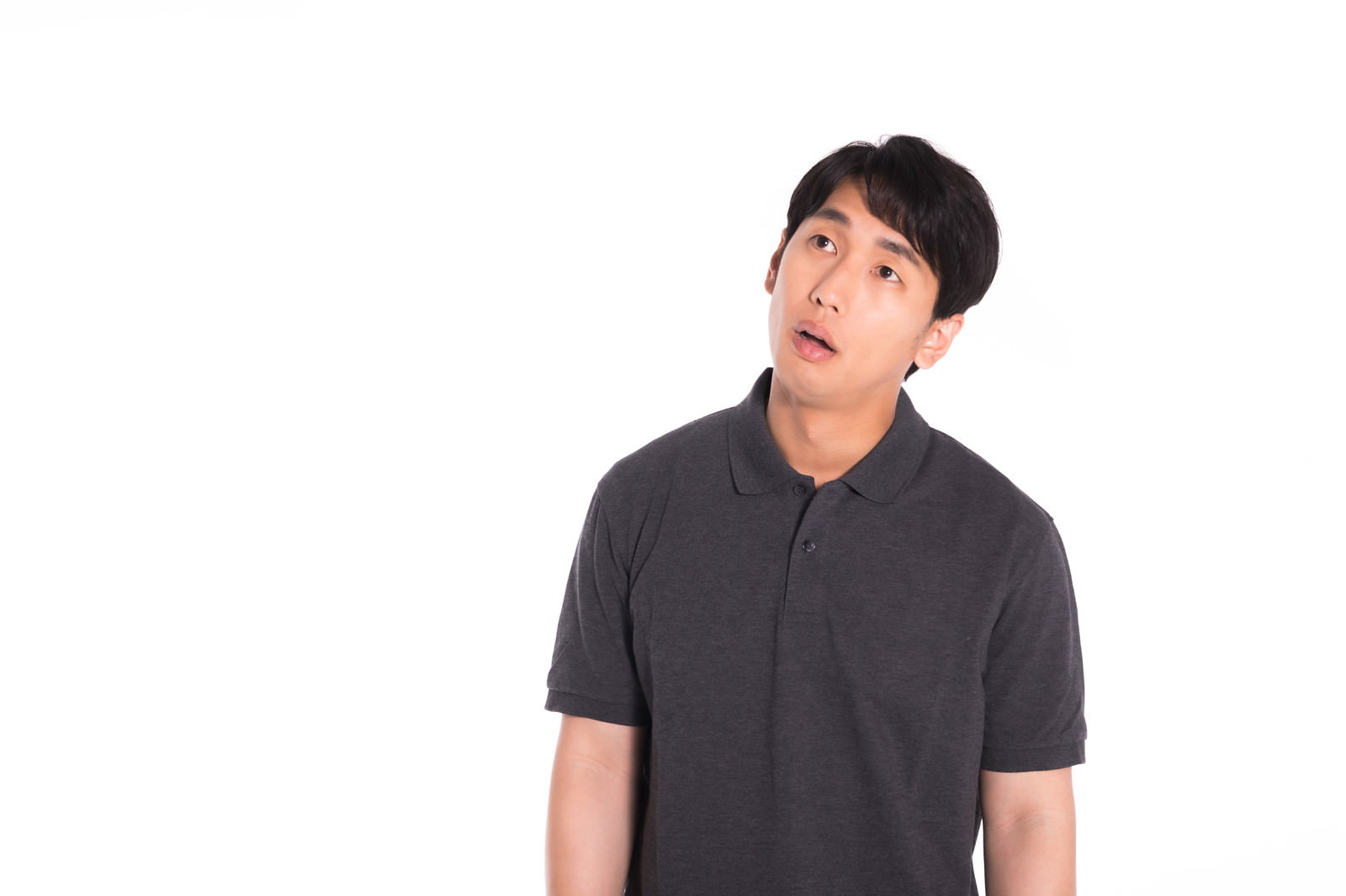 黒いポロシャツを着た男性が上を見上げて無気力な表情をしている［モデル：大川竜弥］