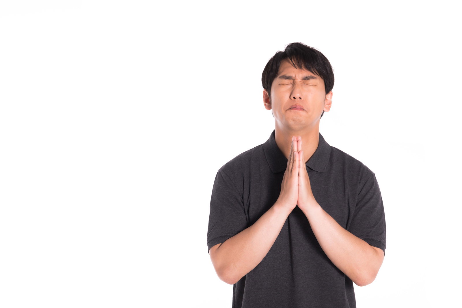 黒いTシャツの男性が両手を合わせて祈るポーズをとっている［モデル：大川竜弥］