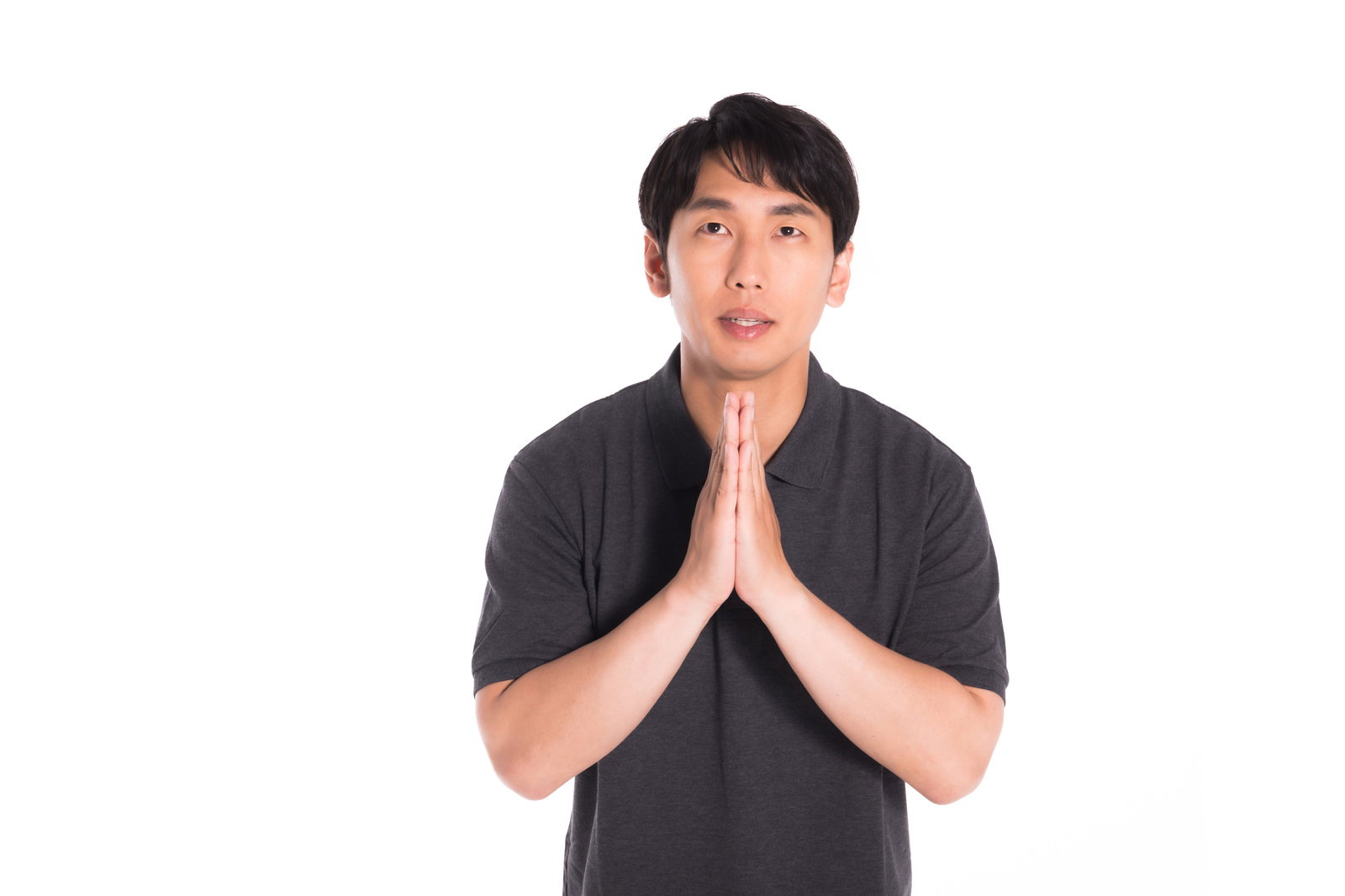 黒い服を着た男性が胸の前で手を合わせて感謝の気持ちを表している［モデル：大川竜弥］