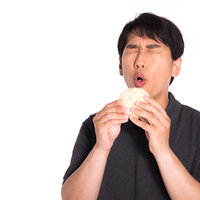 アツアツの肉まんを頬張る食いしん坊な男性の写真