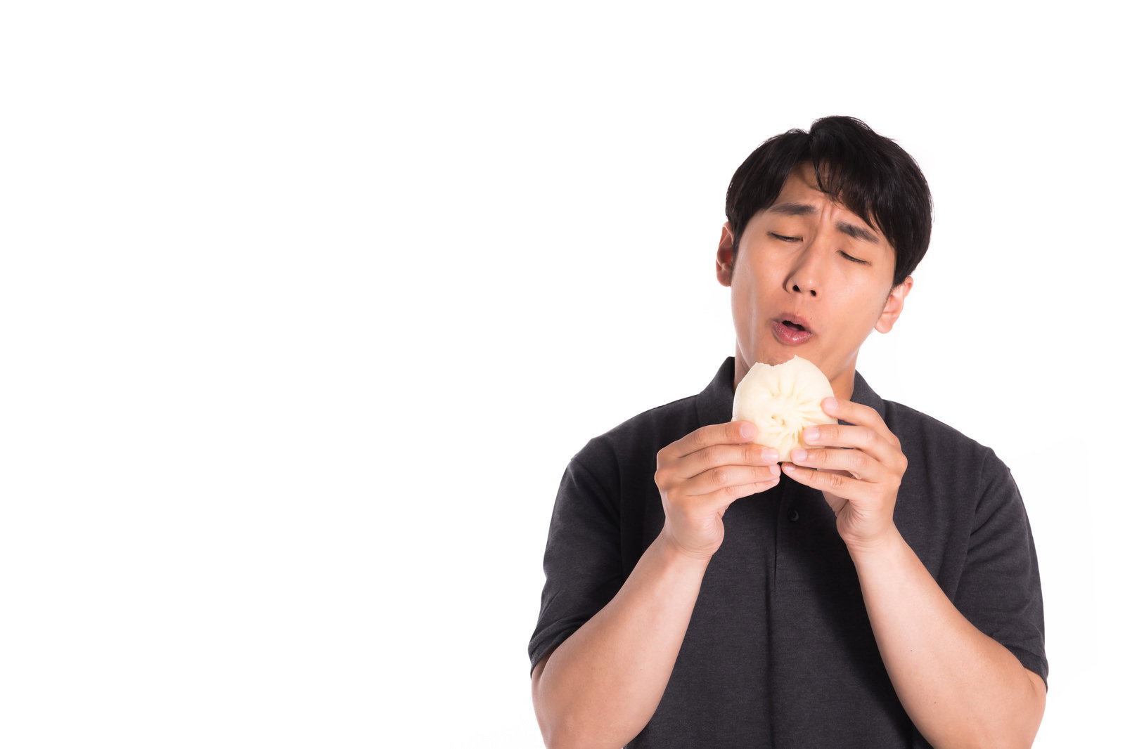 黒いTシャツの男性が両手で豚まんを持ち上を見上げて食べている［モデル：大川竜弥］