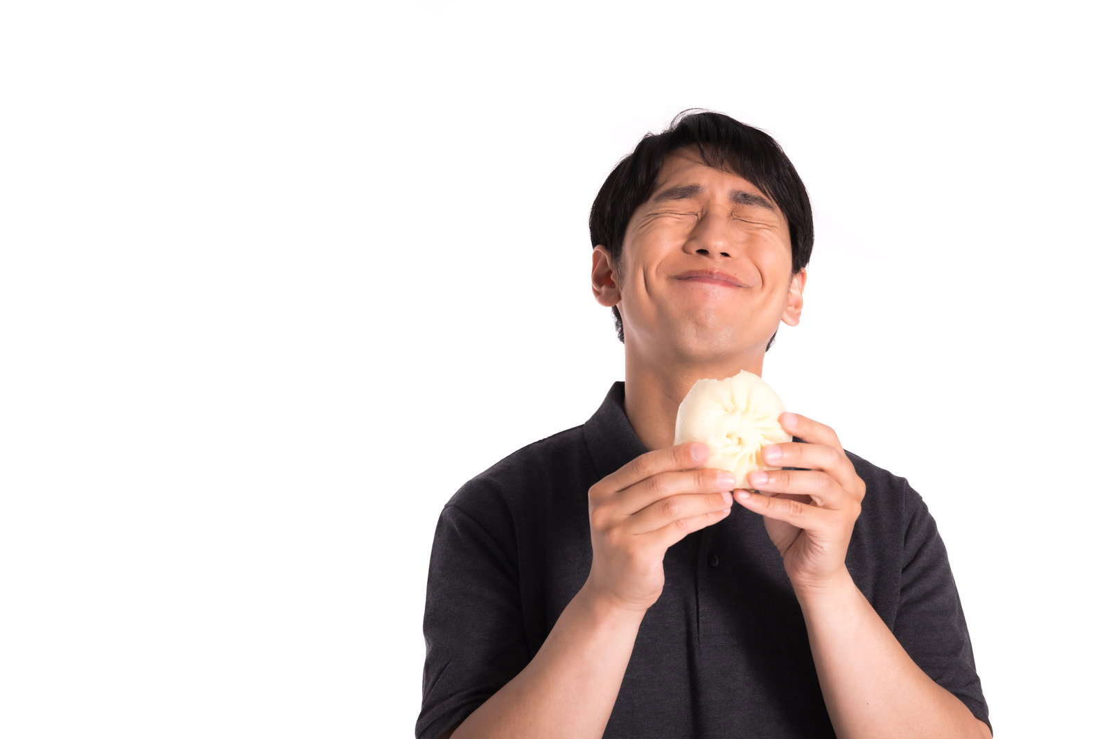 黒いシャツの男性が両手で肉まんを持ち、満面の笑みで頬張っている［モデル：大川竜弥］